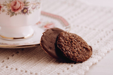 Antique bone china and cookies on a white table dressed with a handmade crochet placemat