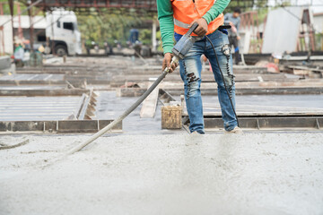 Construction technician uses concrete vibration generator during leveling concrete floor. Construction worker using concrete vibrator removal air bubbles for maximum strength in concrete