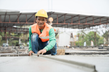 Construction technician working by leveling concrete floor to smooth. Construction worker uses long...