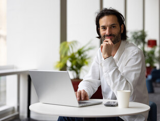 portrait d'un jeune homme souriant assis au bureau devant son ordinateur portable. Concept du...