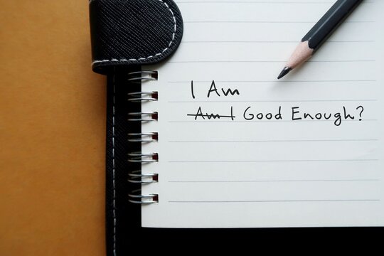 Pencil wrote on notebook AM I GOOD ENOUGH? cross off and change to I AM GOOD ENOUGH - to overcome negative self talk or self doubt, replace inner criticism with positive critical affirmation