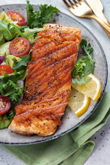 Grilled salmon fish fillet and fresh green lettuce vegetable tomato salad