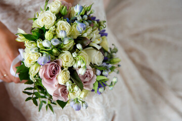 beautiful delicate wedding bouquet of white and pink roses in the hands of the bride