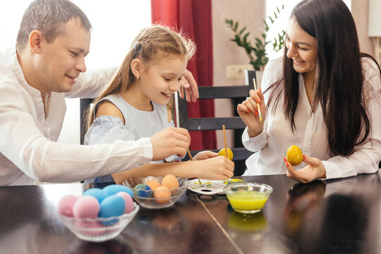 A friendly family paints Easter eggs and laughs.