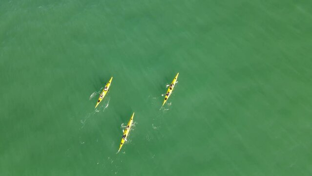 People in three yellow kayaks rowing on the Atlantic Ocean in Uruguay. Aerial view