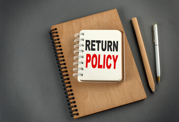RETURN POLICY text on notebook with pen and pencil on grey background - obrazy, fototapety, plakaty
