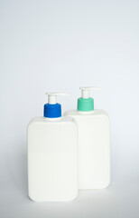Two white cosmetic plastic bottle with pump dispenser pump and blue cap on white background. Liquid container for gel, lotion, cream, shampoo, bath foam.