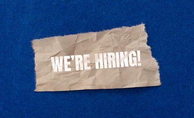 we're hiring! written on ripped paper. Business concept photo.
