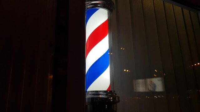 Barber Pole with red, white and blue stripes spinning and marking the place where the hair salon is located