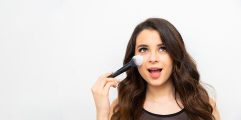 Portrait of a surprised woman applying face powder on the banner with copy space. 