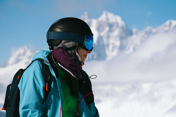 Fototapeta na wymiar Close up portrait of Snowboarder woman standing with mountain peaks covered with snow on background