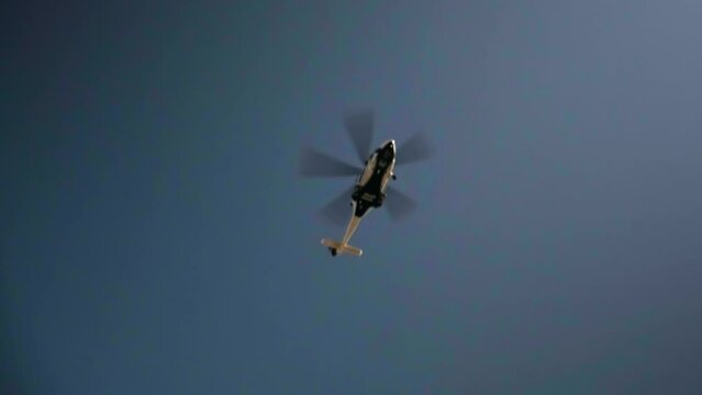 a helicopter flying low over the city against a clear blue sky