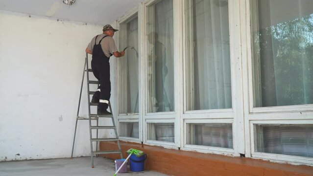 A man window cleaner cleans a window with a silicone or rubber scraper