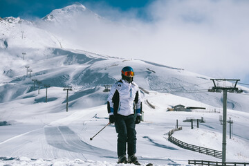 Portrait skier at ski resort standing on sunny day against backdrop of beautiful mountain peaks in...