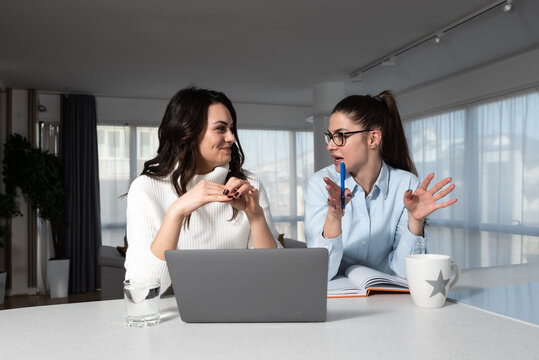 Two Female Friends Business Partners Owners Of Small Interior Decoration And Design Company Sitting And Looking On Laptop Computer Ideas For New Project For Client Who Hired Them To Decorate Property