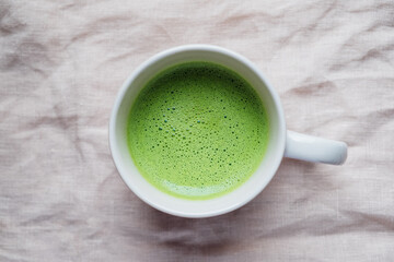 Cup of freshly made delicious matcha tea on neutral beige background. View from above. Morning hot drink.