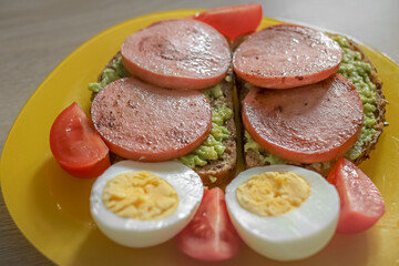 Healthy breakfast. Boiled eggs. Avocado pate. Sandwiches with fried sausage.