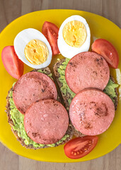 Healthy breakfast. Boiled eggs. Avocado pate. Sandwiches with fried sausage.