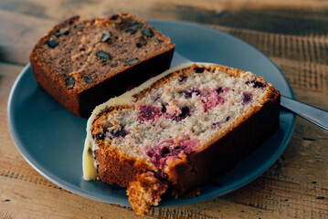 Sweet baked goods like banana bread and loaf cake on plate on wooden background.