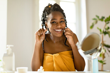 Perfect smile. Portrait of happy black woman using dental floss at home, doing morning routine,...