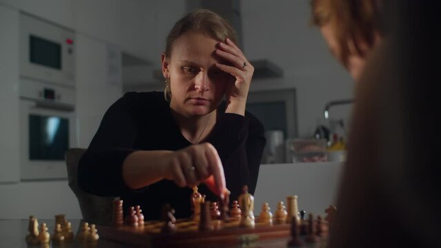Mother and her son compete in a game of chess - medium shot of a woman playing chess with her son at home