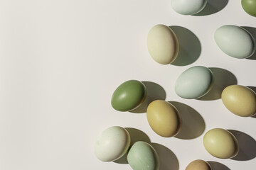 Natural Colorful Easter eggs close up, shadow at sunlight, beige background, copy space. Chicken eggs with natural colored eggshells, food Easter celebration concept, aesthetic flat lay
