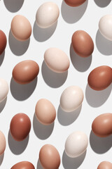 Natural colorful Easter eggs beige brown color on white light background, hard Shadow at sunlight. Modern pattern from Chicken eggs, Easter holiday food, top view, minimal monochrome flat lay
