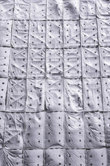 A high-rise building is completely covered with white tarpaulin due to construction work. Full background with copy space for construction sites.