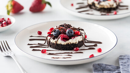 A close up of a mixed berry cheesecake tart, drizzled with melted chocolate.