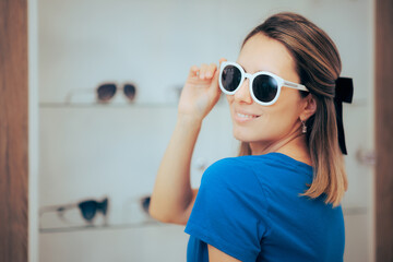 Happy Woman Wearing Sunglasses in a Optical Store. Cheerful girl trying trendy shades on sale
