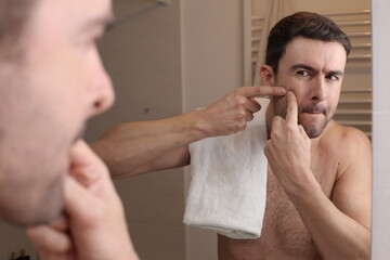 Handsome man removing a pimple 