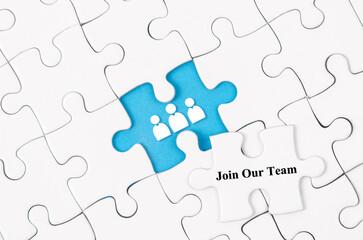 The Join our team concept. White jigsaw puzzle with word and blue background