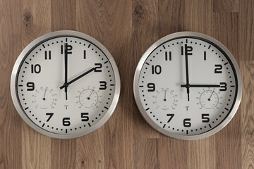 Two clocks, one showing two o'clock, the other showing three o'clock.  Time change symbol. Daylight...