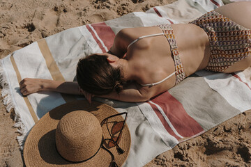 Woman in bikini lays and sunbathing on the beach. Women's fashion accessories. Aesthetic stylish...