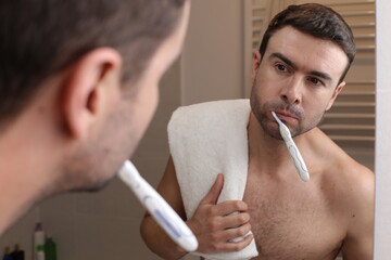 Shirtless man washing his teeth