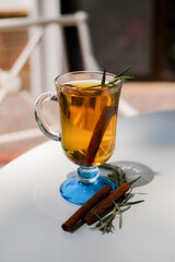 drink with cinnamon and rosemary on a white table. photo on the terrace in the garden