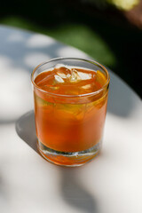 Summer cocktail with fruit and ice. Drink on a white table in the sunlight with the shade of palm leaves. Summer, tropical, fresh cocktail concept.