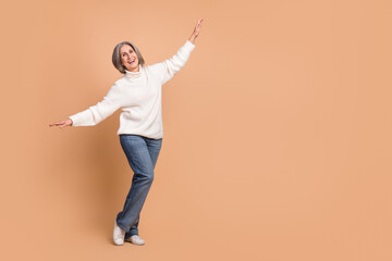 Full body photo of careless old grandmother flying wings weekend relax wear stylish white turtleneck denim jeans isolated on beige color background