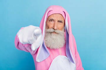 Photo of angry serious pensioner guy dressed bunny kigurumi pointing finger you isolated blue color...