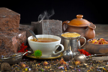 Sweet, hot tea with dry tea leaves, on an old background.