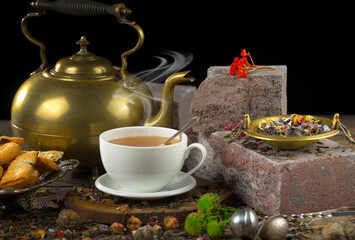 Sweet, hot tea with dry tea leaves, on an old background.