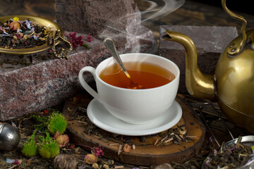 Sweet, hot tea with dry tea leaves, on an old background.