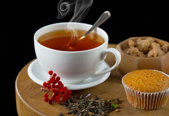Sweet, hot tea with dry tea leaves, on an old background.