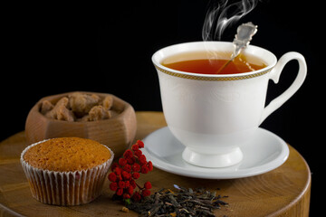 Sweet, hot tea with dry tea leaves, on an old background.