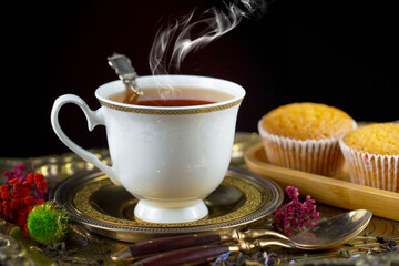 Hot sweet tea in a cup on old background