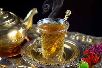 Hot sweet tea in a cup on old background