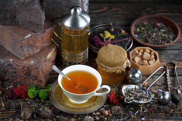 Sweet, hot tea with dry tea leaves, on an old background.
