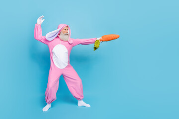 Full length photo of charming cool pensioner guy dressed bunny kigurumi fighting carrot sward empty...