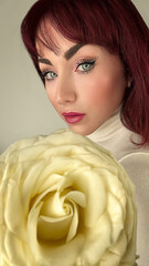 Mujer de ojos azules, posando con rosa amarilla. 