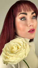Mujer de ojos azules, posando con rosa amarilla. 